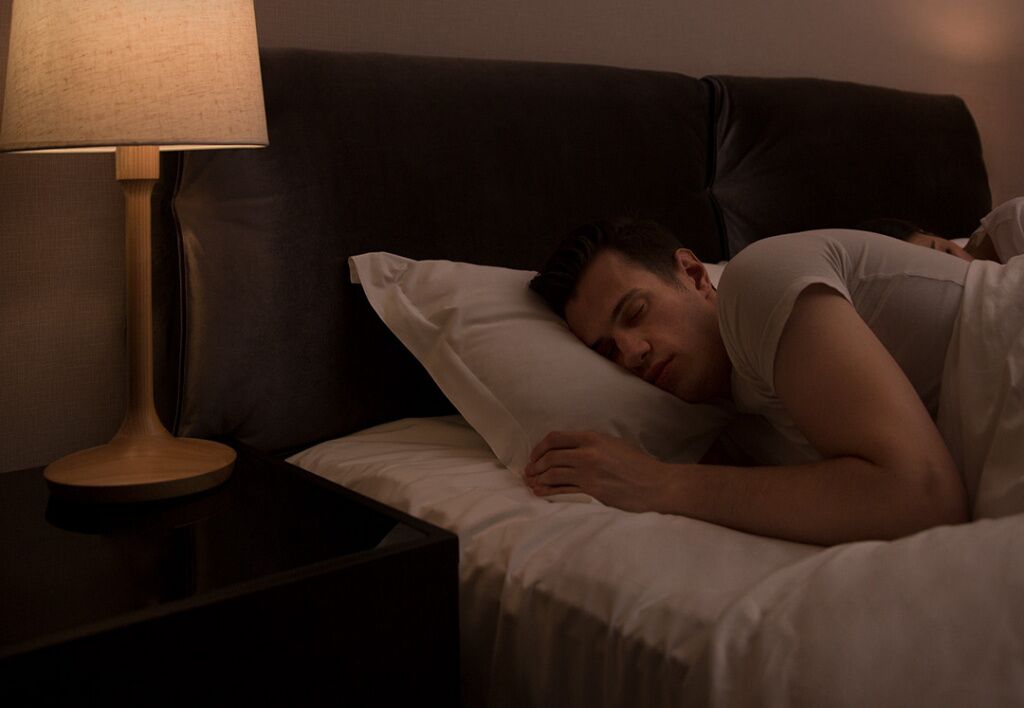 Мужчина спит, лампочка в Smart LED Light Bulb Voice Control светит как ночник